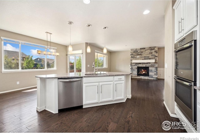 6071 Moran Rd, Timnath, CO 80547 - kitchen with stainless steel appliances, a sink, dark wood-style floors, white cabinets, and baseboards