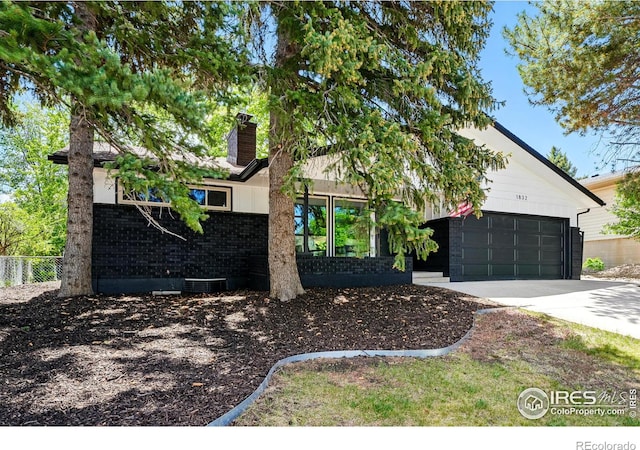 1832 24th Avenue Pl, Greeley, CO 80634 - view of front of home featuring driveway, brick siding, a chimney, and an attached garage