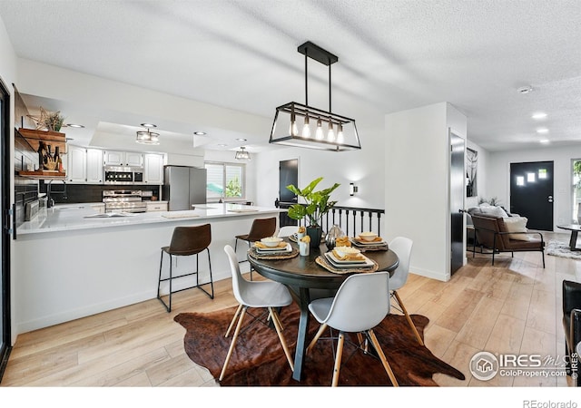 1832 24th Avenue Pl, Greeley, CO 80634 - dining area featuring light wood finished floors, a textured ceiling, and baseboards