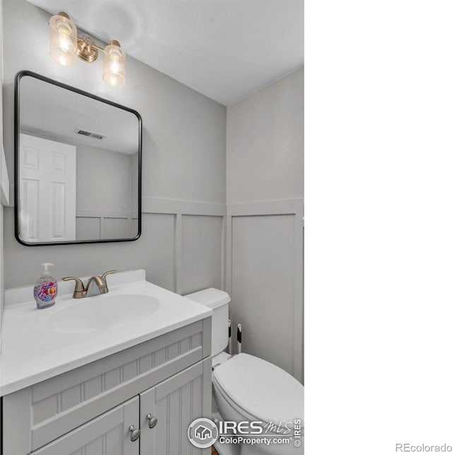 2940 E Yarrow Cir, Superior, CO 80027 - half bath featuring a decorative wall, toilet, vanity, and a wainscoted wall