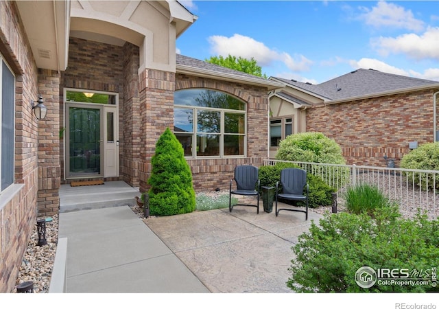 8245 Hidden Cove Ct, Windsor, CO 80528 - property entrance with brick siding, a shingled roof, and a patio
