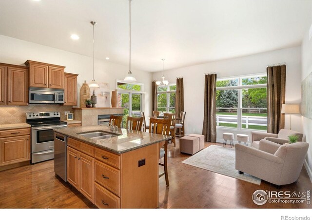 8245 Hidden Cove Ct, Windsor, CO 80528 - kitchen with appliances with stainless steel finishes, a kitchen breakfast bar, a sink, plenty of natural light, and recessed lighting