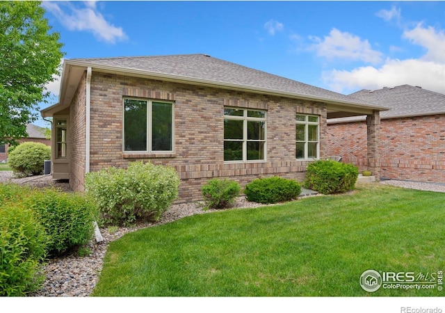 8245 Hidden Cove Ct, Windsor, CO 80528 - view of home's exterior with a yard, brick siding, and roof with shingles