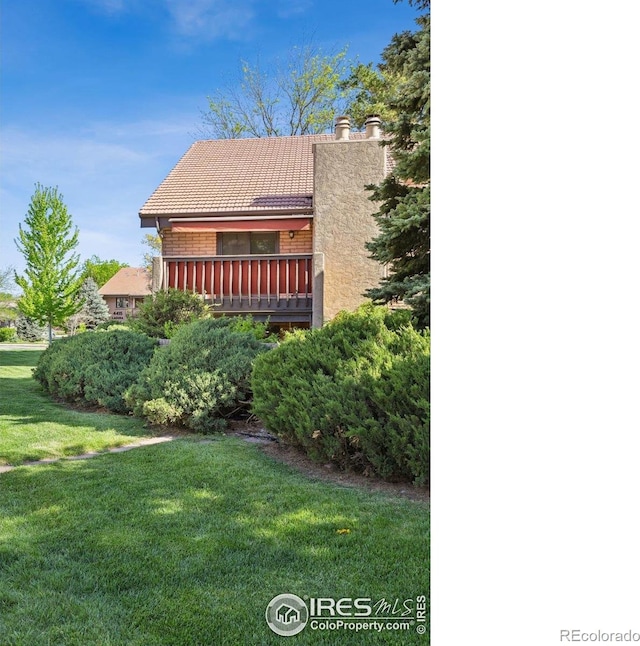 4475 Laguna Pl Unit 201, Boulder, CO 80303 - rear view of house featuring a tiled roof, a lawn, a chimney, and brick siding
