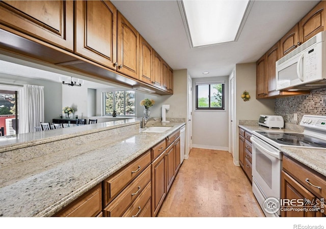 4475 Laguna Pl Unit 201, Boulder, CO 80303 - kitchen with white appliances, a sink, brown cabinets, baseboards, and light wood-type flooring