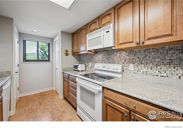 4475 Laguna Pl Unit 201, Boulder, CO 80303 - kitchen with white appliances, brown cabinetry, baseboards, and tasteful backsplash