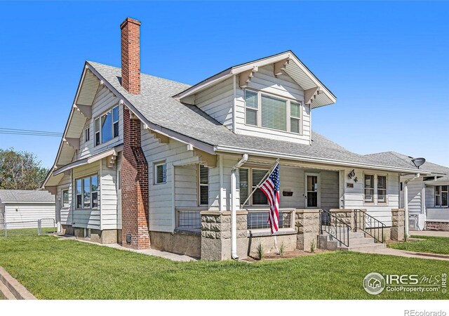 501 Adams Ave, Akron, CO 80720 - view of front facade featuring a chimney, a porch, a front yard, and roof with shingles