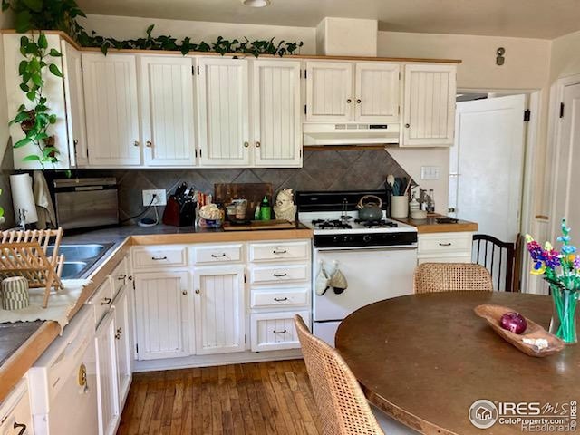 3201 Broadway St, Boulder, CO 80304 - kitchen featuring white gas stove, under cabinet range hood, decorative backsplash, dark wood-type flooring, and white cabinetry