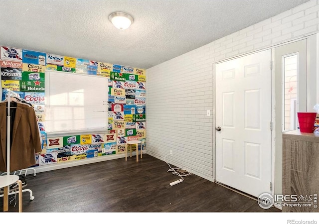 810 W Laurel St, Fort Collins, CO 80521 - recreation room featuring brick wall, wood finished floors, a textured ceiling, baseboards, and healthy amount of natural light