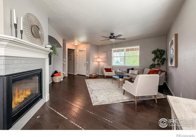 2190 Winding Dr, Longmont, CO 80504 - living room with a glass covered fireplace, a textured ceiling, dark wood-type flooring, and a ceiling fan