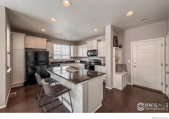 2190 Winding Dr, Longmont, CO 80504 - kitchen featuring black appliances, a kitchen island, white cabinets, a breakfast bar area, and recessed lighting