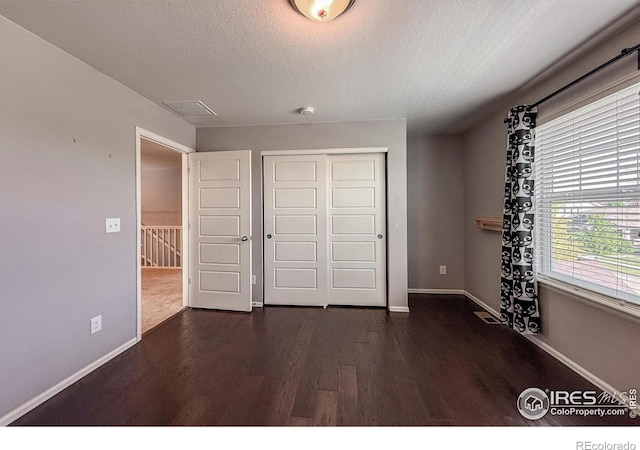 2190 Winding Dr, Longmont, CO 80504 - unfurnished bedroom featuring dark wood-style flooring, a textured ceiling, and a closet