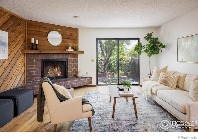 2725 Juniper Ave Unit 78, Boulder, CO 80304 - living room with wooden walls, wood finished floors, a brick fireplace, and a textured ceiling