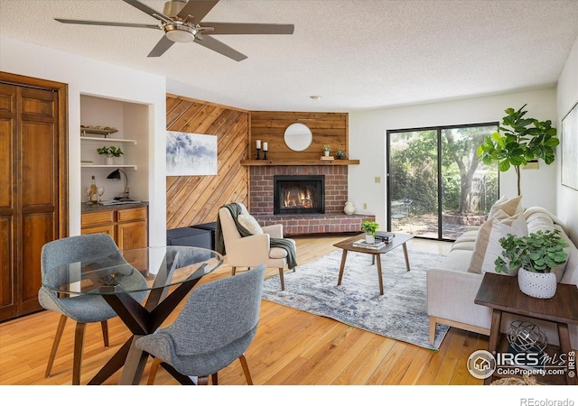 2725 Juniper Ave Unit 78, Boulder, CO 80304 - living room featuring a textured ceiling, wood walls, ceiling fan, light wood-style floors, and a fireplace