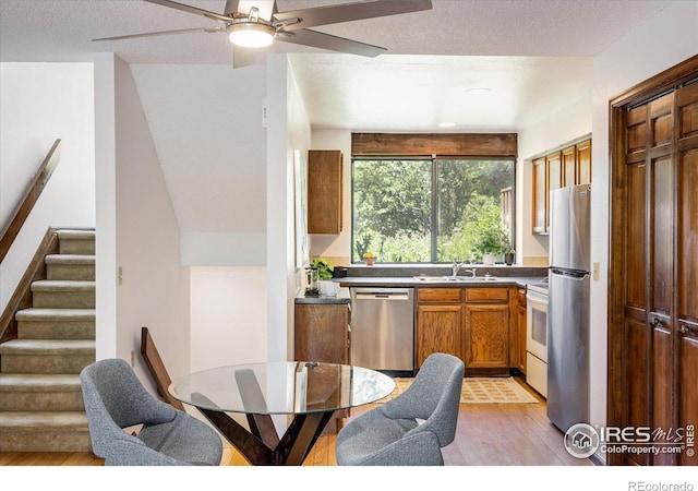 2725 Juniper Ave Unit 78, Boulder, CO 80304 - kitchen with appliances with stainless steel finishes, light wood-type flooring, a sink, dark countertops, and brown cabinets