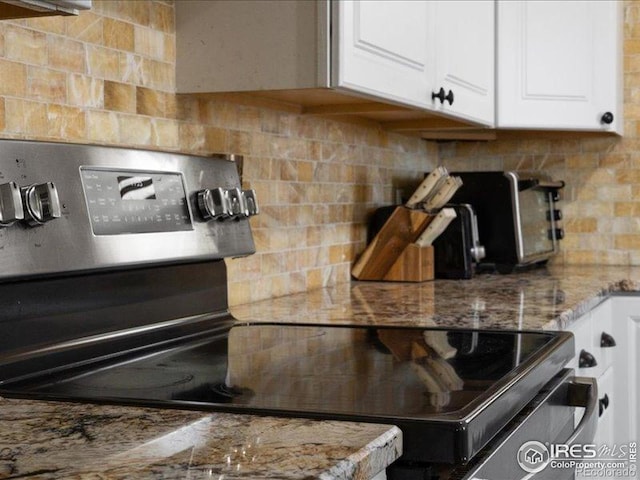 1815 9th Ave, Longmont, CO 80501 - kitchen view of backsplash, white cabinetry, stainless steel range with electric stovetop, and light stone countertops
