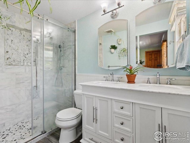1815 9th Ave, Longmont, CO 80501 - bathroom featuring a stall shower, toilet, a wainscoted wall, and double vanity