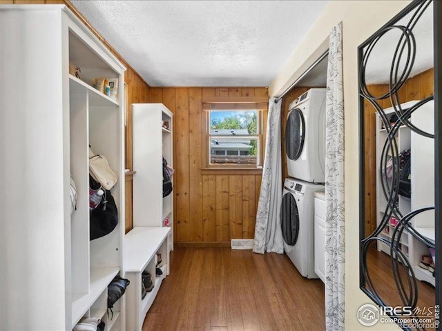 1815 9th Ave, Longmont, CO 80501 - washroom with stacked washer / drying machine, a textured ceiling, wood finished floors, and wood walls