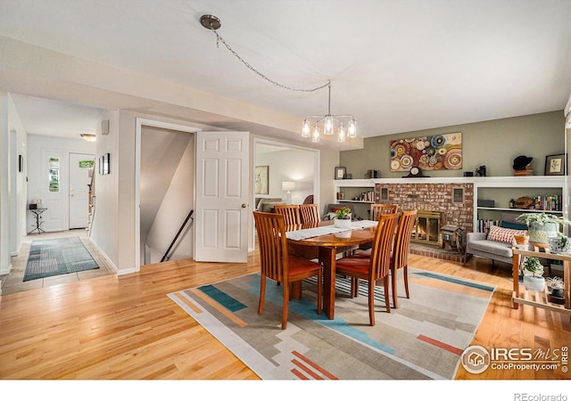1119 Oakmont Ct, Fort Collins, CO 80525 - dining room with light wood finished floors, a brick fireplace, and a chandelier