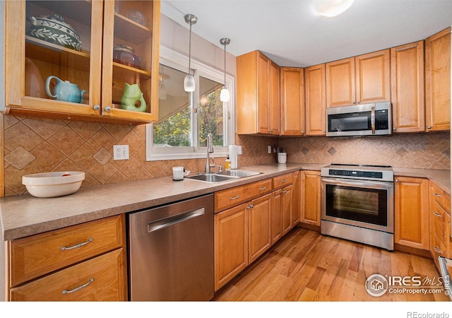 1119 Oakmont Ct, Fort Collins, CO 80525 - kitchen with stainless steel appliances, a sink, light wood-type flooring, pendant lighting, and decorative backsplash
