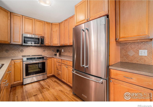 1119 Oakmont Ct, Fort Collins, CO 80525 - kitchen featuring appliances with stainless steel finishes, decorative backsplash, and light wood-type flooring