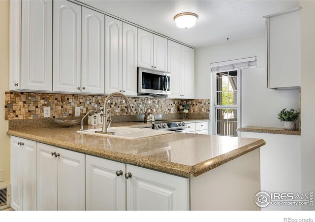911 Homer Cir, Lafayette, CO 80026 - kitchen with stainless steel appliances, tasteful backsplash, white cabinetry, and light stone counters