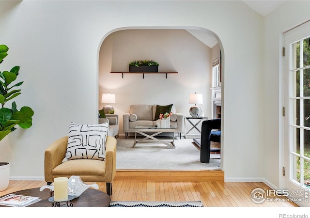 911 Homer Cir, Lafayette, CO 80026 - living area featuring arched walkways, hardwood / wood-style flooring, a fireplace, baseboards, and lofted ceiling