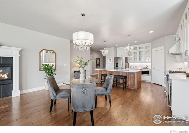 1948 Tidewater Ln, Windsor, CO 80550 - dining area featuring a chandelier, hardwood / wood-style flooring, recessed lighting, a glass covered fireplace, and baseboards