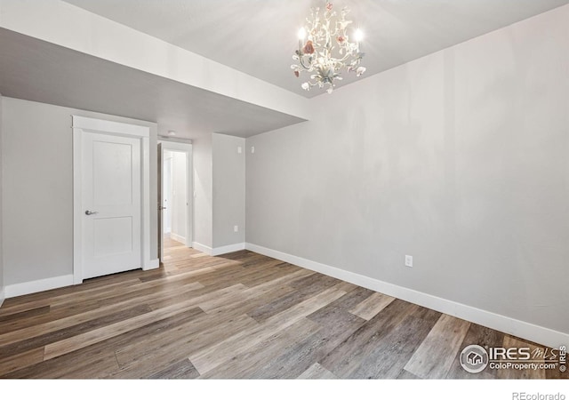 1948 Tidewater Ln, Windsor, CO 80550 - spare room featuring wood finished floors, baseboards, and a chandelier