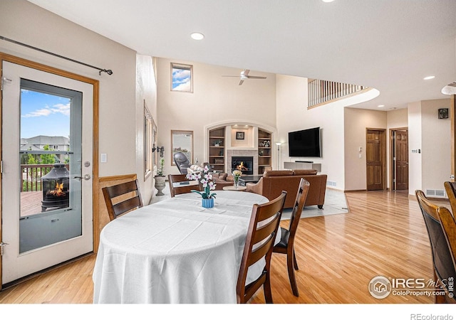 13971 Telluride Dr, Broomfield, CO 80020 - dining space with a glass covered fireplace, a ceiling fan, light wood finished floors, recessed lighting, and built in shelves