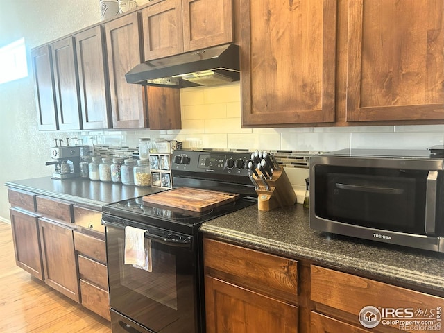 368 Mt Bross Ave, Severance, CO 80550 - kitchen featuring black / electric stove, under cabinet range hood, stainless steel microwave, light wood finished floors, and decorative backsplash