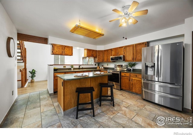 4118 Dillon Way, Fort Collins, CO 80526 - kitchen featuring appliances with stainless steel finishes, stone tile flooring, ceiling fan, and brown cabinetry