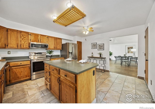4118 Dillon Way, Fort Collins, CO 80526 - kitchen with appliances with stainless steel finishes, dark countertops, a ceiling fan, and a kitchen island