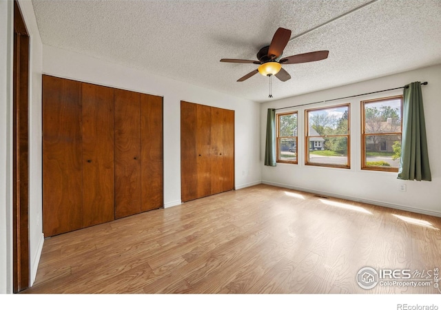 4118 Dillon Way, Fort Collins, CO 80526 - unfurnished bedroom with light wood finished floors, multiple closets, a textured ceiling, a ceiling fan, and baseboards