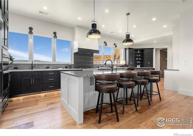 2387 Harding Park Ct, Berthoud, CO 80513 - kitchen featuring a center island with sink, a sink, a kitchen bar, decorative backsplash, and open shelves