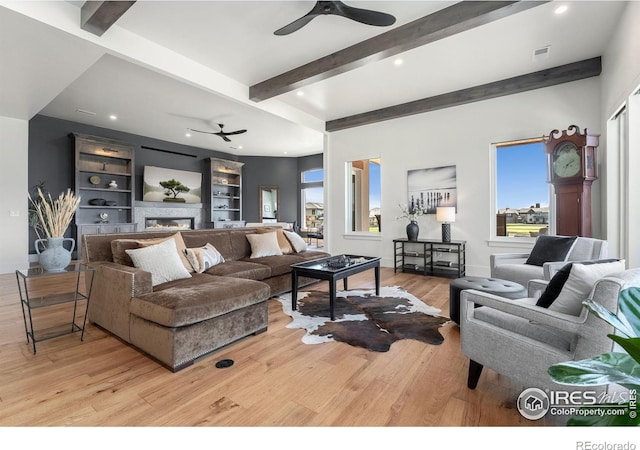 2387 Harding Park Ct, Berthoud, CO 80513 - living room with a ceiling fan, wood finished floors, beamed ceiling, a glass covered fireplace, and built in shelves