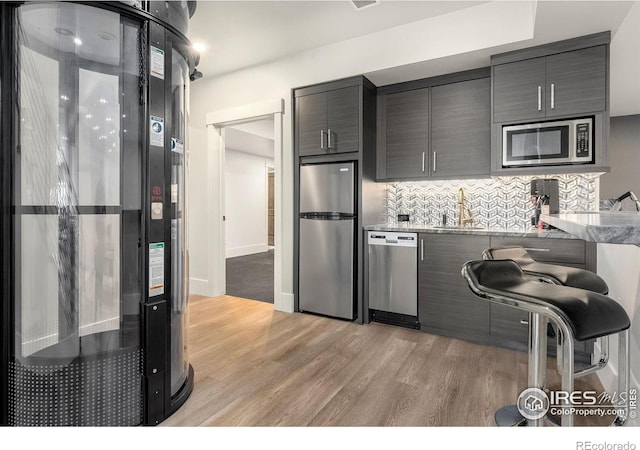 2387 Harding Park Ct, Berthoud, CO 80513 - kitchen featuring appliances with stainless steel finishes, light wood finished floors, tasteful backsplash, a sink, and modern cabinets