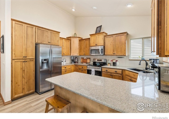 6848 Pettigrew St, Wellington, CO 80549 - kitchen with appliances with stainless steel finishes, a sink, a peninsula, light wood-style floors, and tasteful backsplash