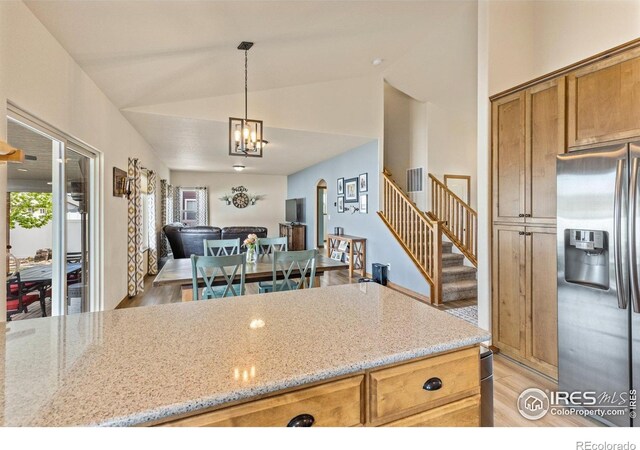 6848 Pettigrew St, Wellington, CO 80549 - kitchen featuring stainless steel fridge, arched walkways, lofted ceiling, light stone countertops, and open floor plan