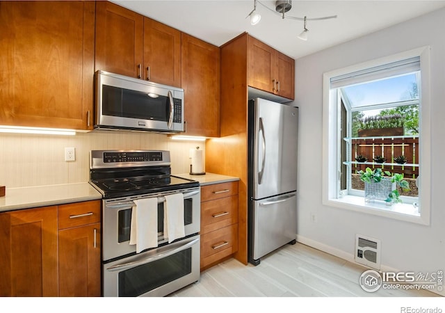 4795 Tantra Dr, Boulder, CO 80305 - kitchen featuring stainless steel appliances, brown cabinetry, light countertops, baseboards, and backsplash