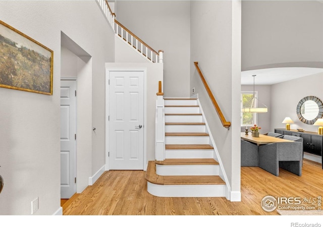 5348 Wild Dunes Ct, Boulder, CO 80301 - stairs with wood finished floors, arched walkways, baseboards, and a towering ceiling