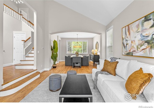 5348 Wild Dunes Ct, Boulder, CO 80301 - living area featuring arched walkways, wood finished floors, high vaulted ceiling, stairs, and baseboards