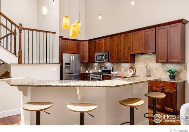 4924 Clubhouse Ct, Boulder, CO 80301 - kitchen with appliances with stainless steel finishes, a kitchen breakfast bar, backsplash, light wood-style flooring, and light stone counters