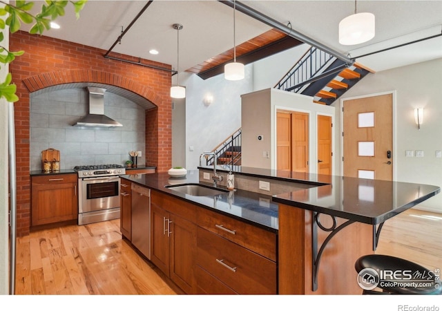 1203 High St, Boulder, CO 80304 - kitchen with appliances with stainless steel finishes, a sink, wall chimney range hood, light wood finished floors, and decorative light fixtures