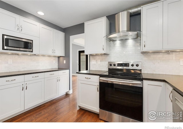 531 S 9th St, Berthoud, CO 80513 - kitchen featuring stainless steel appliances, wall chimney exhaust hood, dark countertops, tasteful backsplash, and recessed lighting