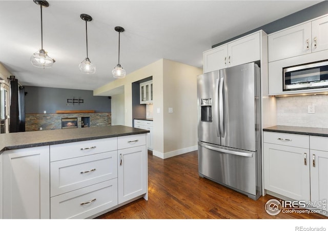531 S 9th St, Berthoud, CO 80513 - kitchen featuring appliances with stainless steel finishes, dark countertops, decorative backsplash, and white cabinetry