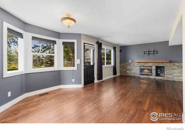 531 S 9th St, Berthoud, CO 80513 - unfurnished living room featuring wood finished floors, a stone fireplace, and baseboards