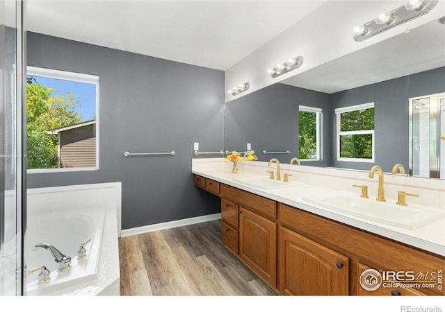 531 S 9th St, Berthoud, CO 80513 - bathroom featuring wood finished floors, a garden tub, double vanity, and baseboards