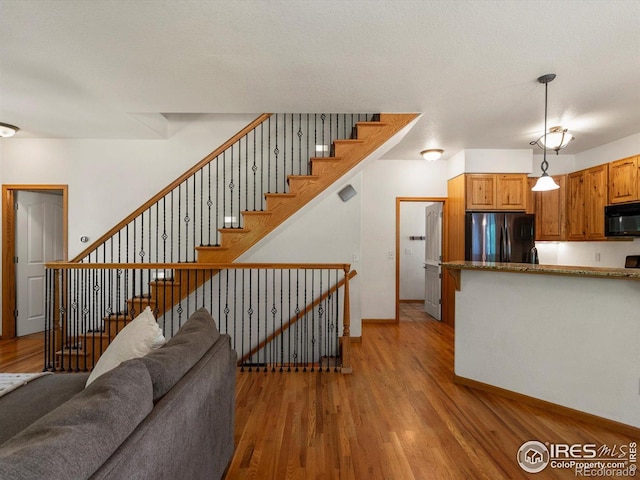 101 SE 2nd St, Berthoud, CO 80513 - kitchen with refrigerator, black microwave, light wood-style floors, and decorative light fixtures