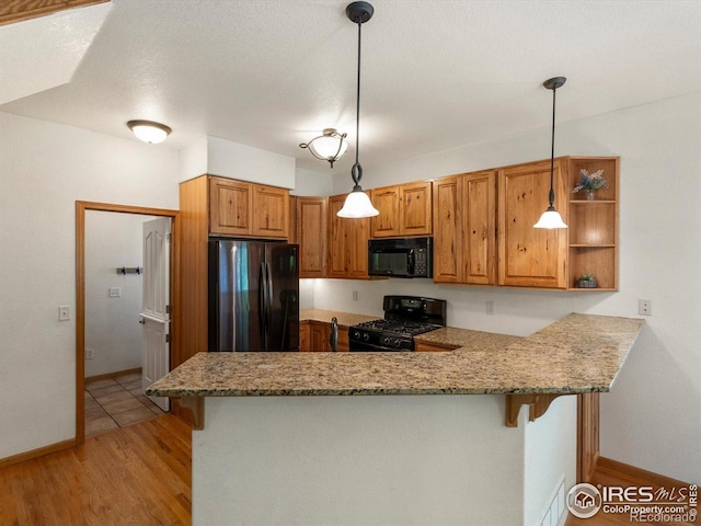101 SE 2nd St, Berthoud, CO 80513 - kitchen featuring black appliances, a peninsula, brown cabinets, a kitchen bar, and light stone countertops